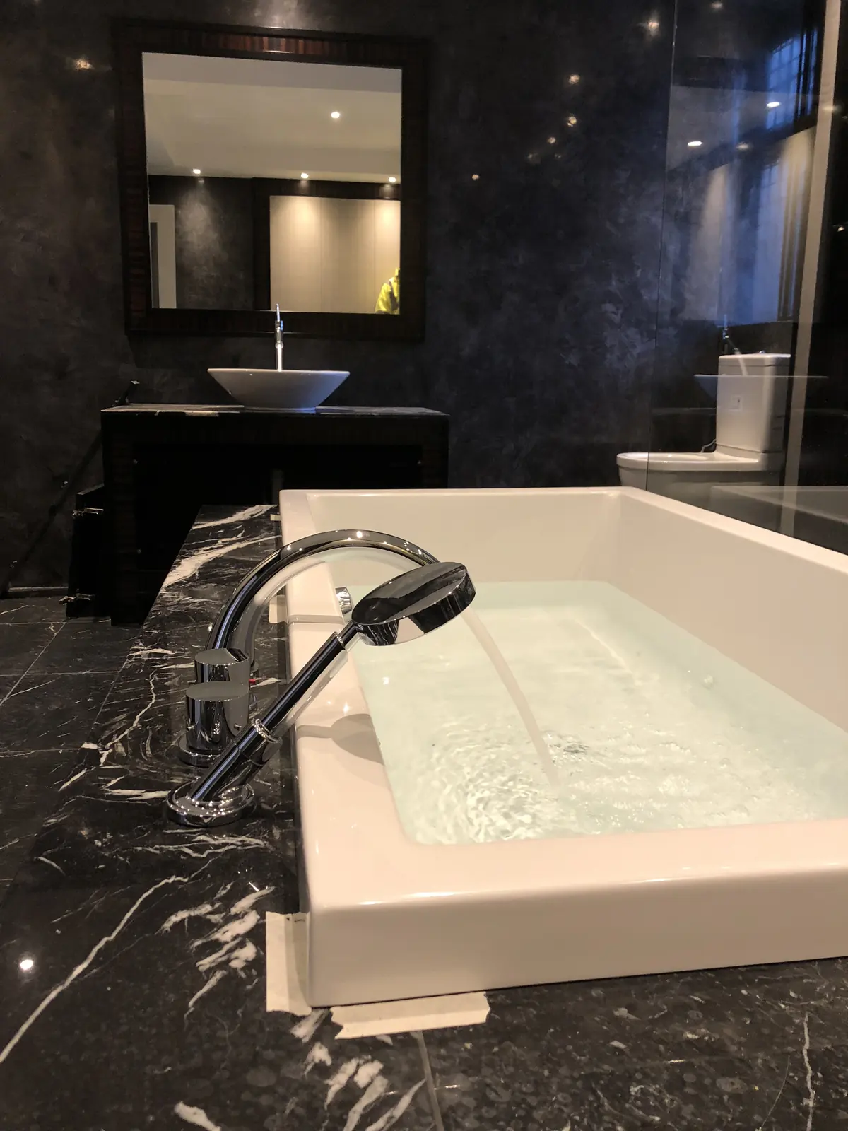 Inset bath in black marble with a waterfall tap